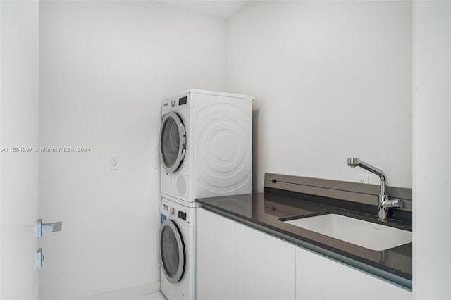 laundry room featuring cabinets, sink, and stacked washer and clothes dryer