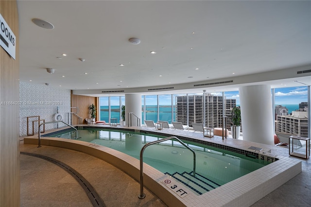 view of pool with a hot tub and a water view