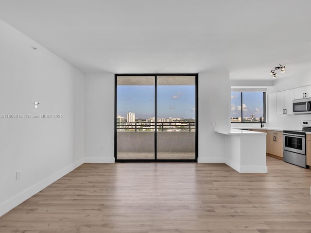 interior space with track lighting, baseboards, and light wood-type flooring