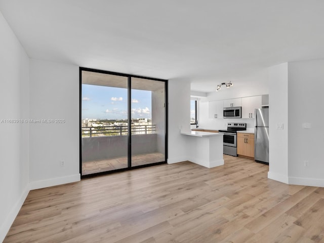 unfurnished living room with baseboards, floor to ceiling windows, and light wood-style flooring