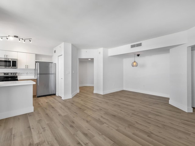 kitchen with stainless steel appliances, light countertops, visible vents, light wood-style floors, and white cabinetry