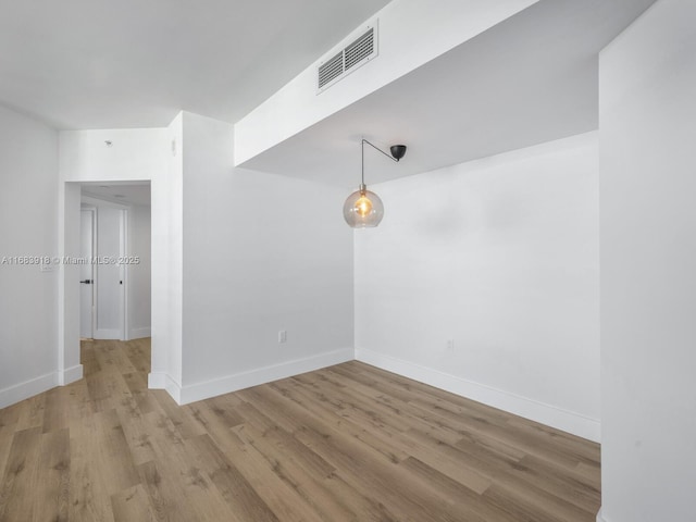 spare room with light wood finished floors, visible vents, and baseboards