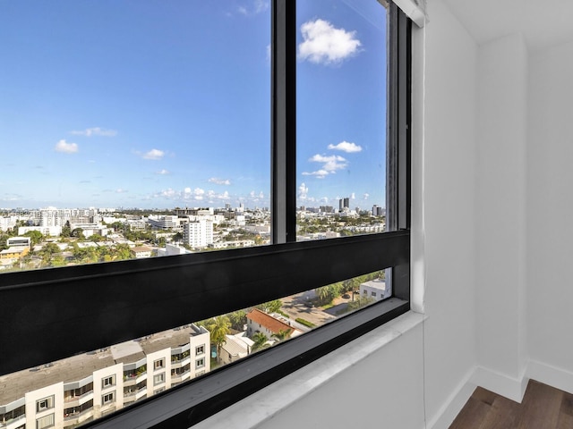 interior details with a city view, wood finished floors, and baseboards