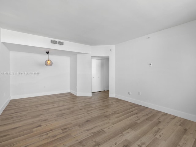 unfurnished room with light wood-style floors, baseboards, and visible vents