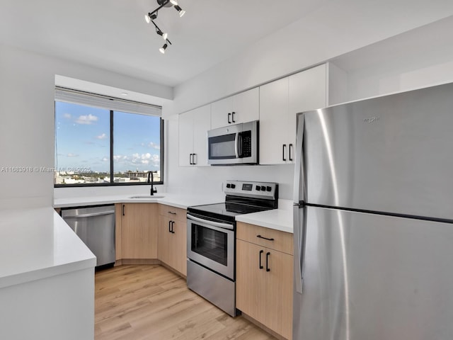 kitchen with light countertops, appliances with stainless steel finishes, light brown cabinets, and a sink