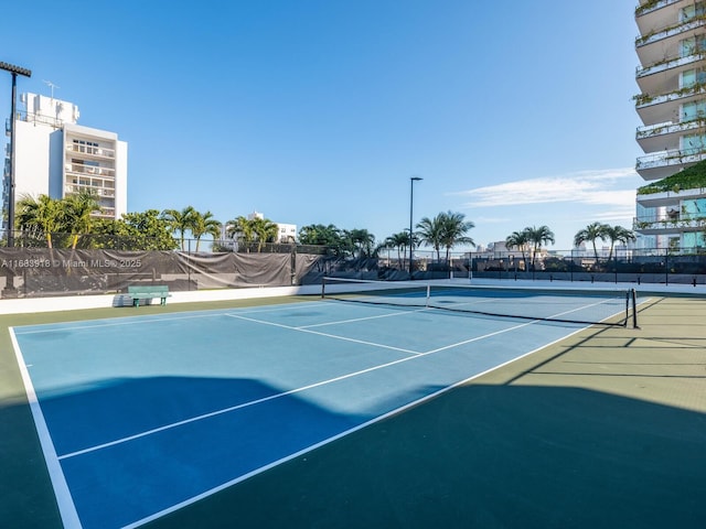view of tennis court featuring community basketball court and fence