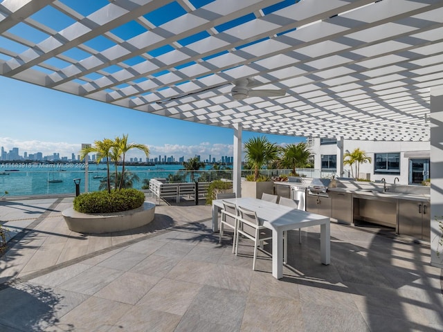 view of patio with a pergola, an outdoor kitchen, ceiling fan, outdoor dining space, and a view of city