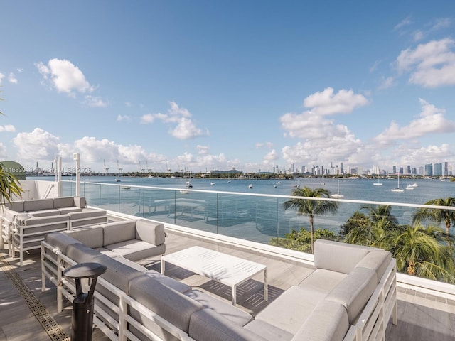 view of patio featuring a view of city, a water view, a balcony, and an outdoor hangout area