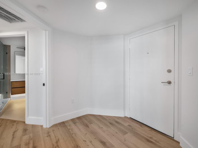 unfurnished room with visible vents, light wood finished floors, and baseboards