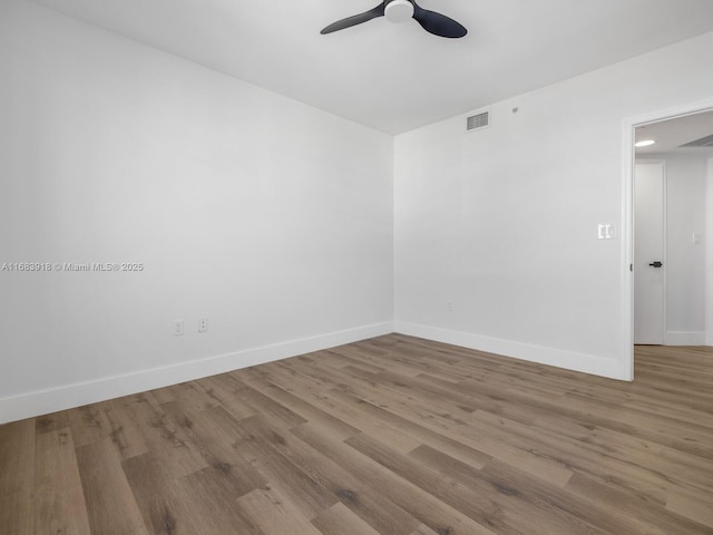 empty room featuring a ceiling fan, baseboards, visible vents, and wood finished floors