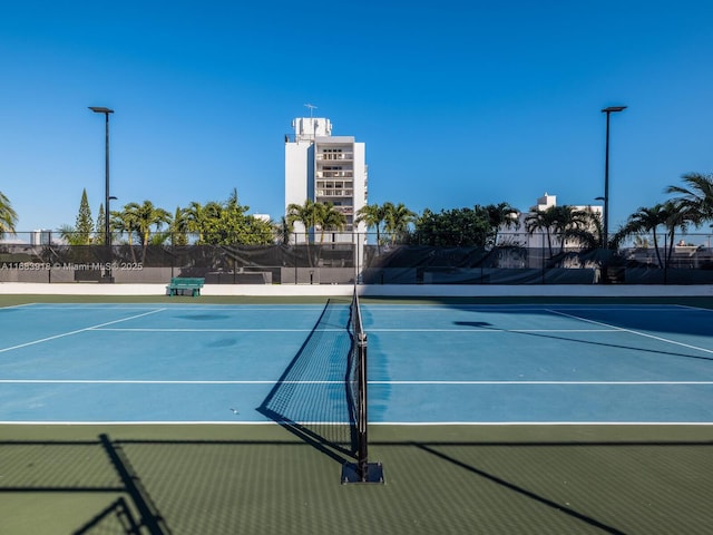 view of tennis court with community basketball court and fence