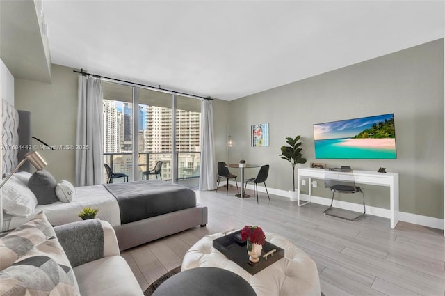 bedroom featuring floor to ceiling windows, access to exterior, and light hardwood / wood-style flooring