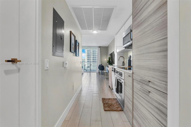 kitchen with white cabinetry, electric panel, light hardwood / wood-style floors, stainless steel appliances, and floor to ceiling windows