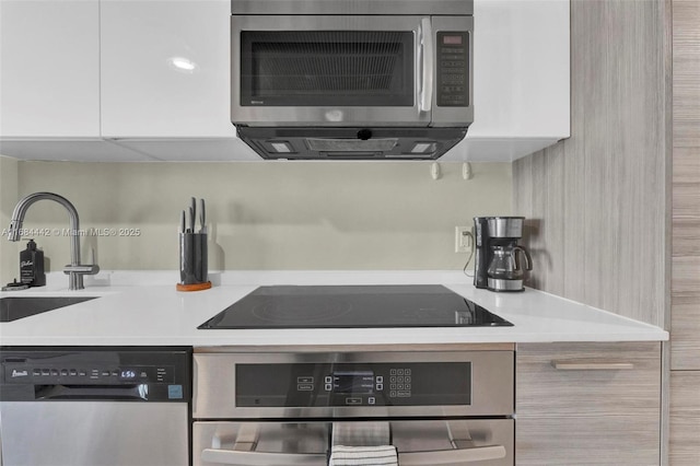 kitchen with stainless steel appliances, sink, and white cabinets