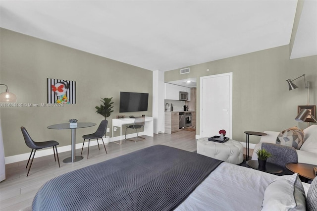 bedroom featuring light hardwood / wood-style floors and sink