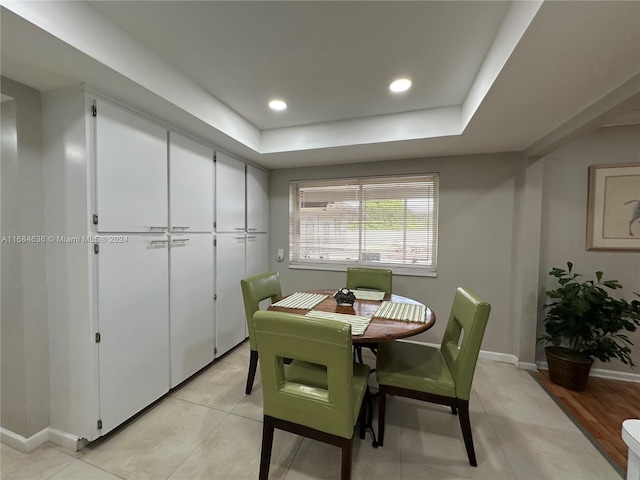 dining room featuring light wood-type flooring and a raised ceiling