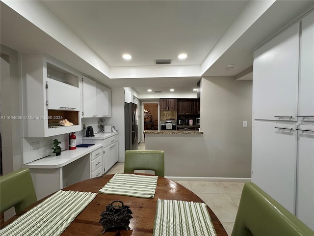 kitchen with a raised ceiling, white cabinetry, stainless steel appliances, and light tile patterned floors