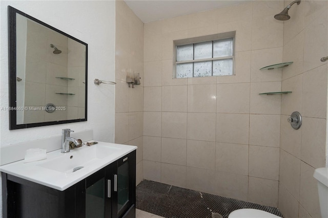 bathroom with vanity, toilet, and a tile shower