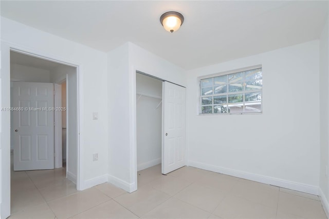 unfurnished bedroom with light tile patterned floors and a closet