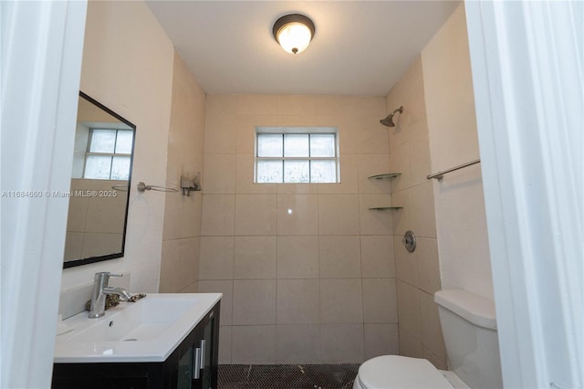 bathroom with vanity, tiled shower, and toilet