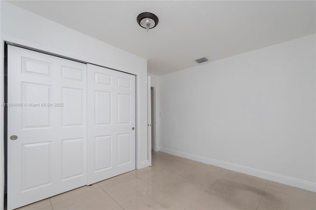 unfurnished bedroom featuring light tile patterned floors and a closet