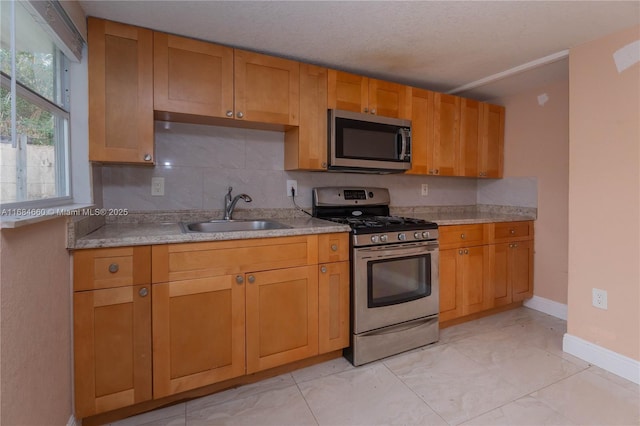 kitchen featuring stainless steel appliances, tasteful backsplash, sink, and a textured ceiling