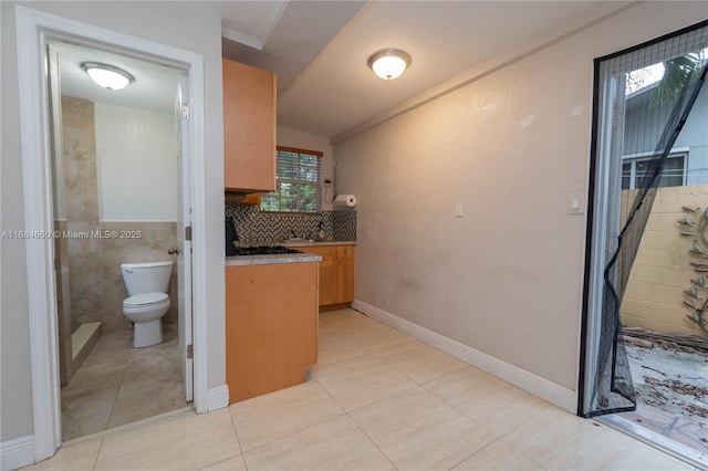 interior space with tasteful backsplash, light tile patterned floors, and a healthy amount of sunlight