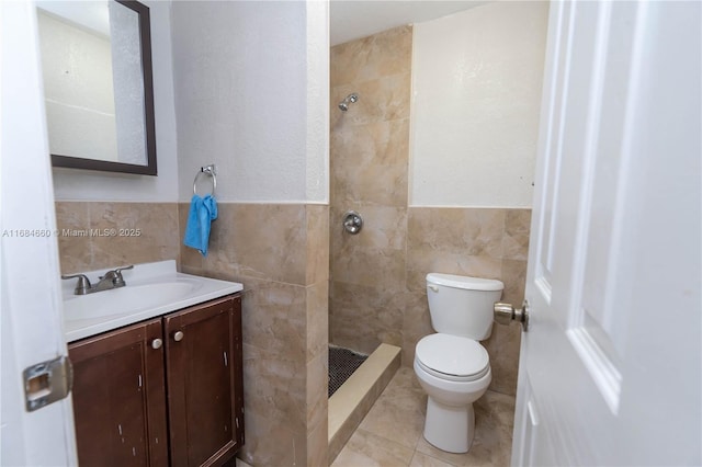 bathroom featuring tile patterned floors, toilet, tile walls, a tile shower, and vanity