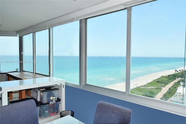 sunroom featuring a water view and a beach view