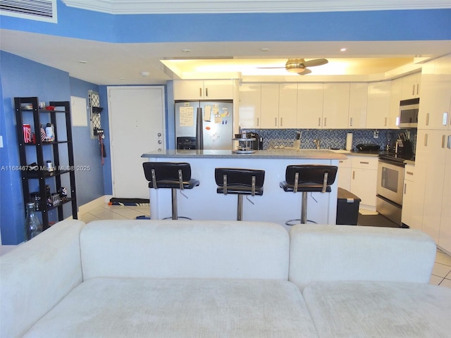 kitchen with light tile patterned floors, a kitchen bar, white cabinets, visible vents, and appliances with stainless steel finishes