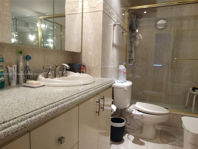 bathroom featuring toilet, a shower with door, tile walls, tile patterned flooring, and vanity