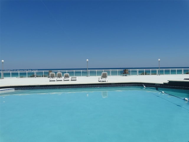 pool with fence and a water view