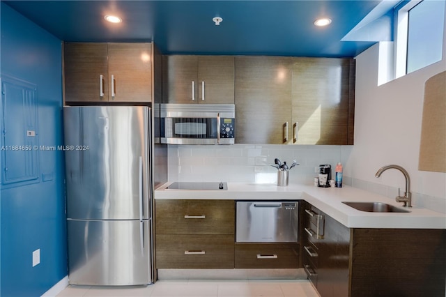 kitchen with decorative backsplash, dark brown cabinets, stainless steel appliances, sink, and light tile patterned floors