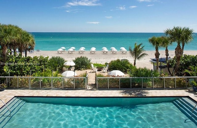 view of pool with a water view and a view of the beach