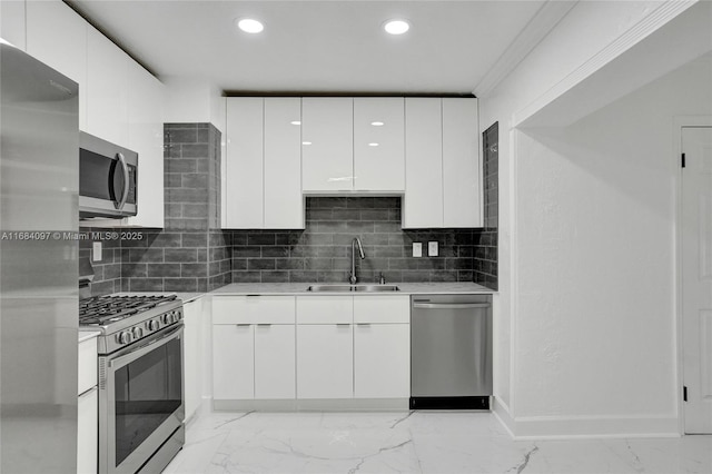 kitchen featuring sink, appliances with stainless steel finishes, ornamental molding, white cabinets, and decorative backsplash