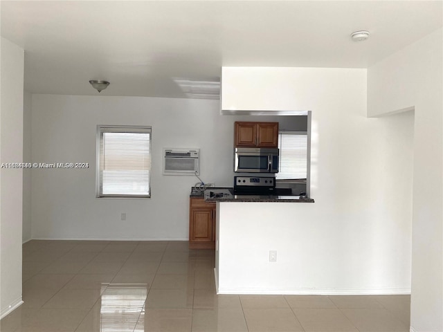 kitchen with a wall mounted air conditioner, stainless steel appliances, a healthy amount of sunlight, and light tile patterned floors