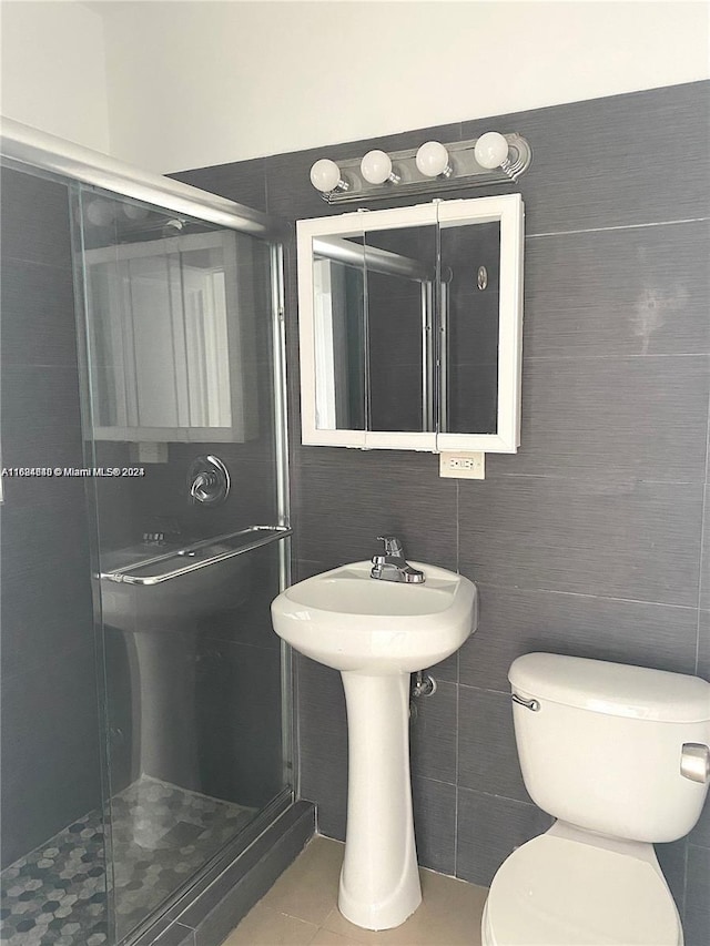 bathroom with a shower with door, tile walls, and toilet