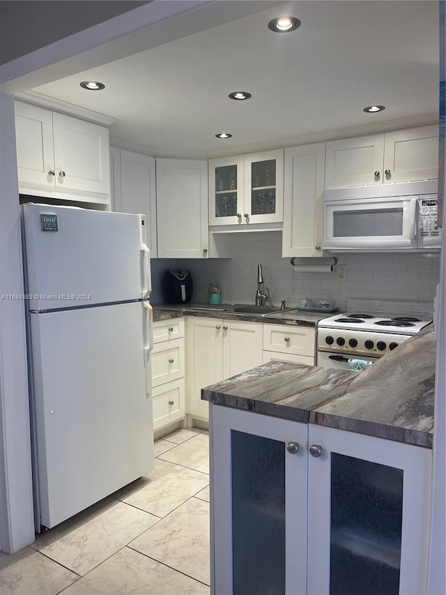 kitchen with white appliances, tasteful backsplash, white cabinetry, and sink