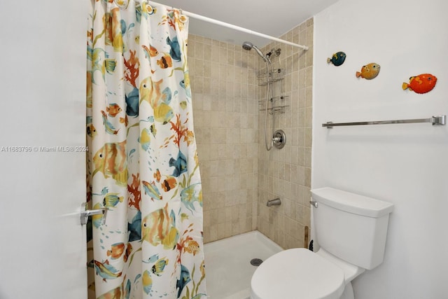 bathroom featuring toilet and curtained shower