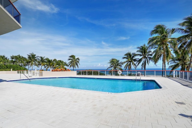 view of swimming pool featuring a patio and a water view