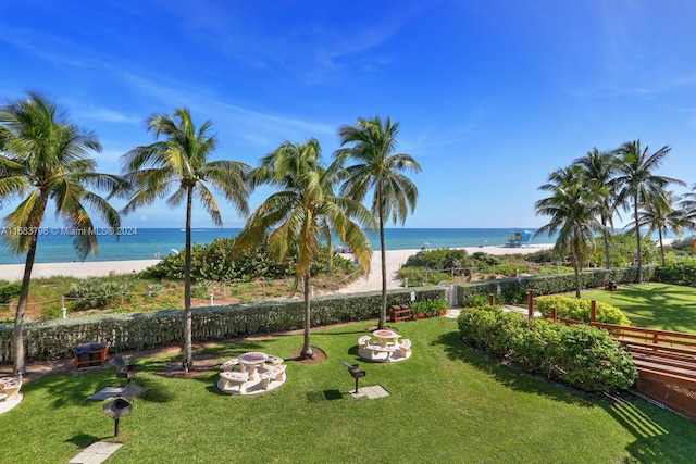 view of community featuring a water view, a fire pit, and a beach view