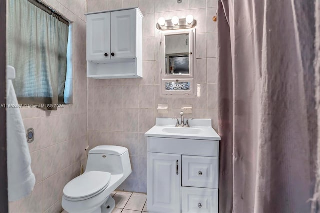 bathroom with tile patterned flooring, vanity, toilet, and tile walls