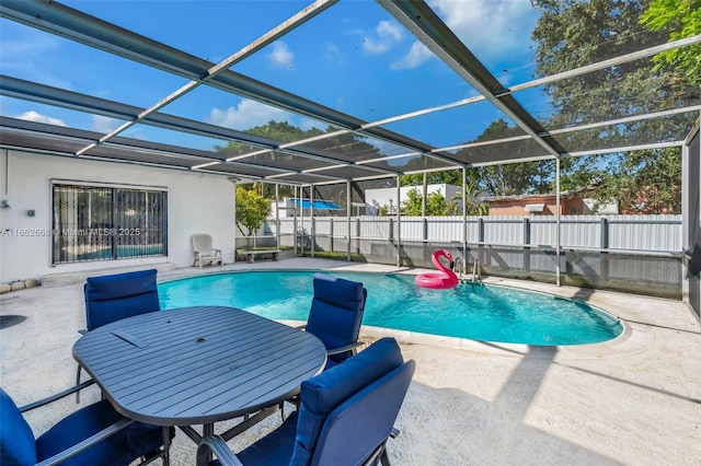 view of pool with glass enclosure and a patio