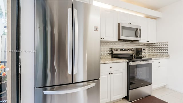 kitchen featuring light tile patterned floors, appliances with stainless steel finishes, backsplash, white cabinetry, and light stone countertops