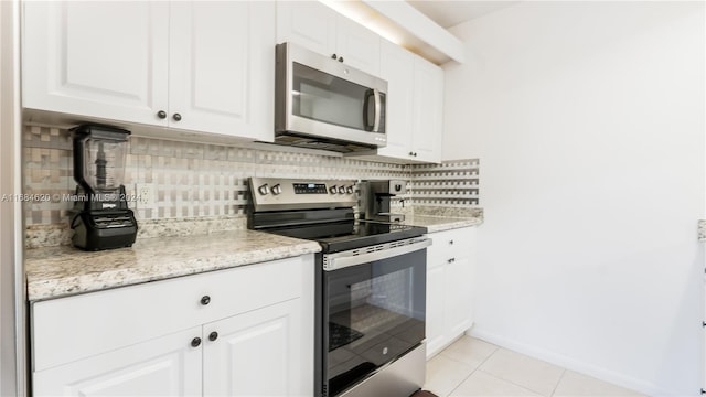 kitchen featuring decorative backsplash, white cabinets, stainless steel appliances, and light tile patterned floors