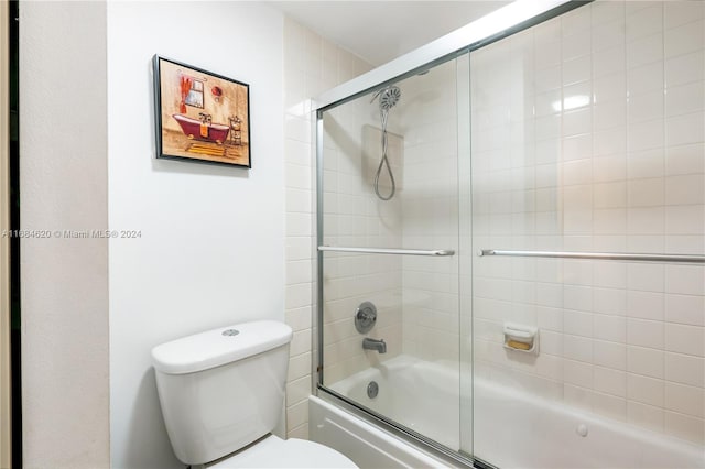 bathroom featuring toilet and combined bath / shower with glass door