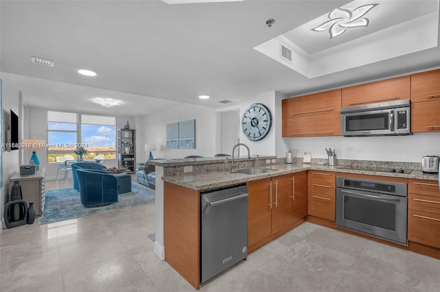 kitchen featuring kitchen peninsula, light stone countertops, stainless steel appliances, and sink