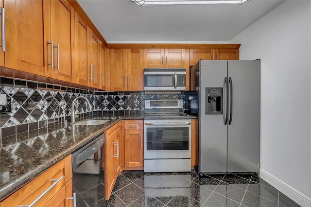 kitchen with dark stone countertops, stainless steel appliances, decorative backsplash, and sink