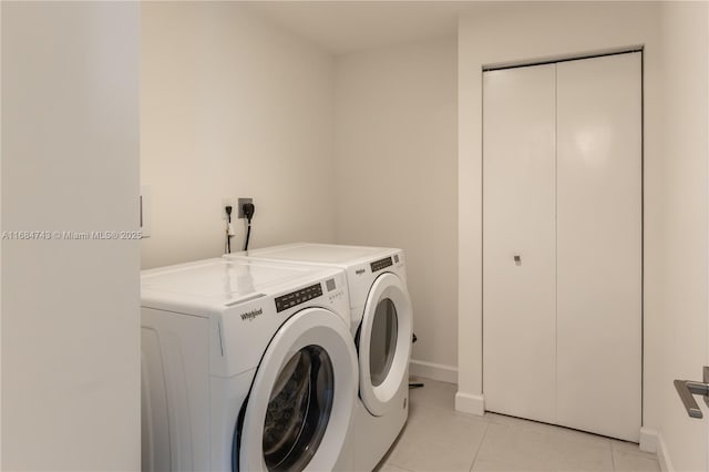 clothes washing area featuring washer and clothes dryer and light tile patterned flooring