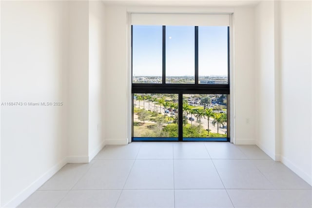 spare room with expansive windows, plenty of natural light, and light tile patterned flooring